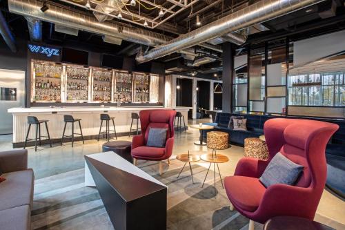 a lobby with red chairs and a bar at Aloft Omaha Aksarben Village in Omaha