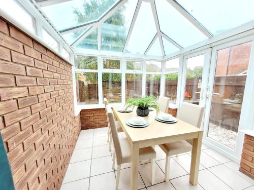 a conservatory dining room with a table and chairs at Stay @ Enville Close, Birmingham Airport & NEC in Marston Green