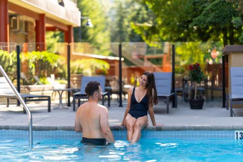a man and a woman sitting in a swimming pool at Whistler Village Inn & Suites in Whistler