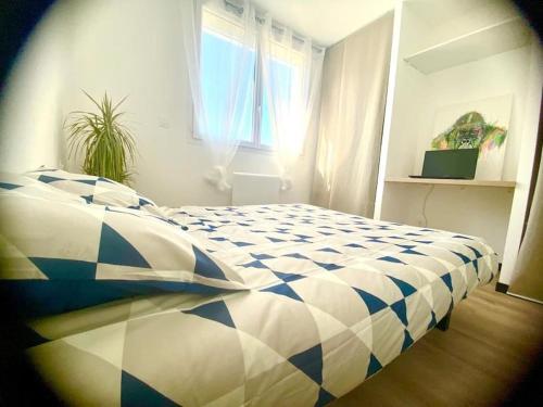 a blue and white bed in a room with a window at *Superbe appartement moderne* in Lourdes