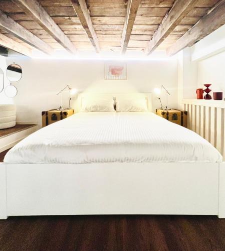 uma cama branca num quarto branco com tectos em madeira em Tarra Luxury Suite em Milão