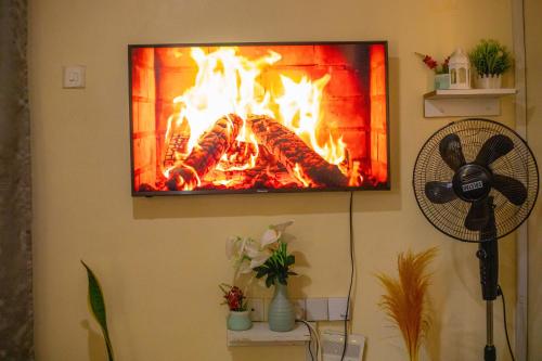 a tv hanging on a wall with a fireplace at Tom Mboya Estate - Fast WI-FI, Netflix and Parking 1Br Apartment in Kisumu Town in Kisumu