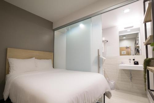 a bedroom with a white bed and a sink at SOVA Micro-Room & Social Hotel in Dallas