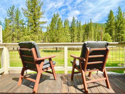 two rocking chairs sitting on a wooden deck at Swing into Summer at our Mountain Home with a River View in Blairsden