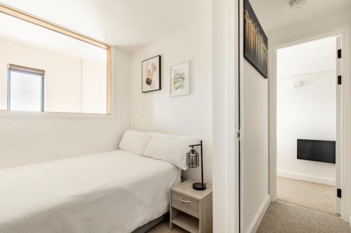 a white bedroom with a bed and a window at Two Bedrooms Exquisite En-Suite Apartment Deansgate in Manchester