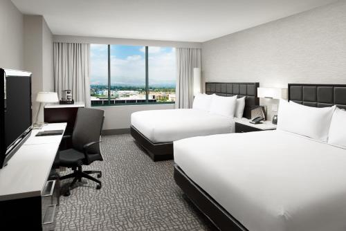 a hotel room with two beds and a desk at Hilton Woodland Hills/ Los Angeles in Woodland Hills
