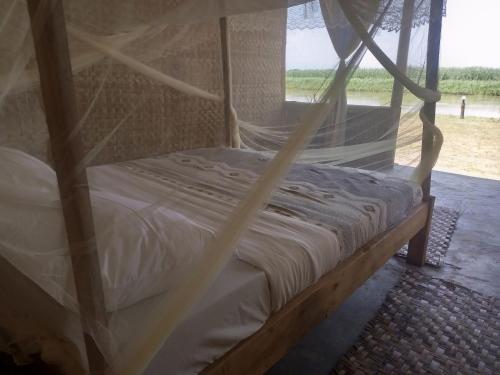 Bett in einem Zimmer mit Moskitonetz in der Unterkunft Semliki Fishing River Camp 