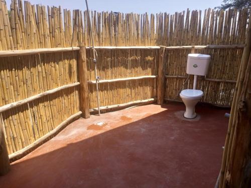 a bathroom with a toilet in a fence at Semliki Fishing River Camp 