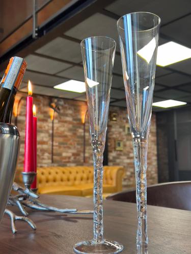 two empty glasses sitting on a table with a bottle of wine at ALL - Amberstone Lux Loft in Klaipėda