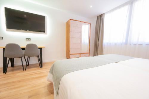 a bedroom with a bed and a desk and a tv at Laguna Home & Suites in La Laguna