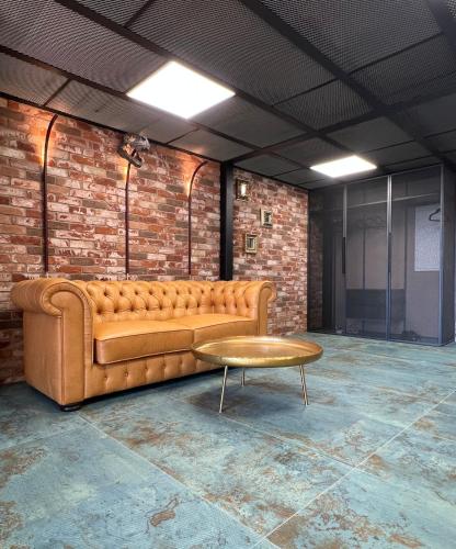 a couch in a room with a brick wall at ALL - Amberstone Lux Loft in Klaipėda