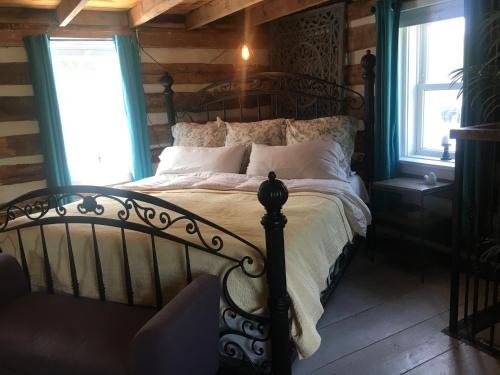 a bedroom with a bed in a room with wooden walls at Historic 1850 Log Cabin in Westminster