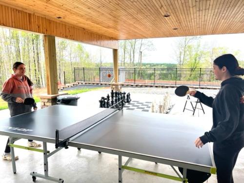 due persone intorno a un tavolo da ping pong di Broad River Campground Cabins & Domes a Boiling Springs