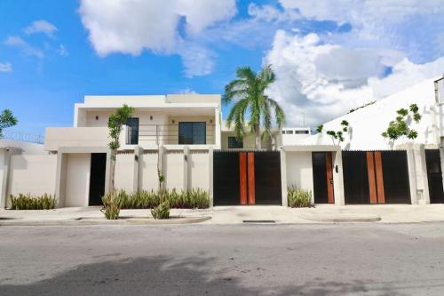 a white house with a palm tree in front of it at Casa Belcher in Cozumel