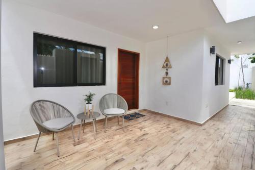 een woonkamer met 2 stoelen, een tafel en een tv bij Casa Belcher in Cozumel