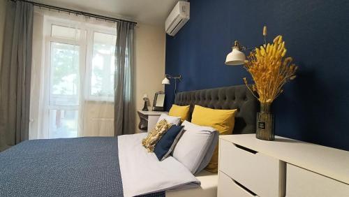 Dormitorio azul con cama con almohadas amarillas en Relax Point Plus Apartment en Irpin'