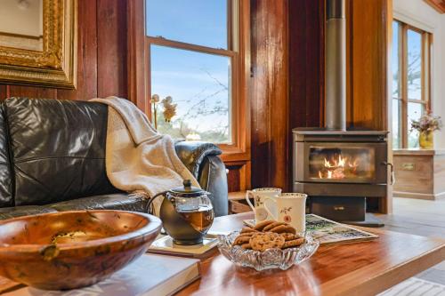 a living room with a table with a wood stove at Christophers Cottage in Bilpin