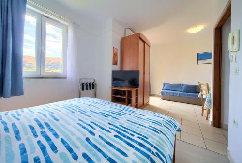 a bedroom with a bed and a flat screen tv at Apartments Ada in Baška