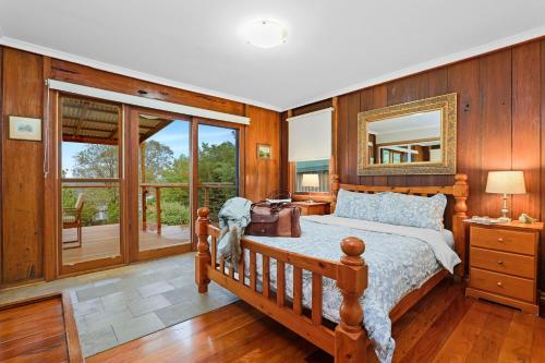 1 dormitorio con cama y espejo en la pared en Christophers Cottage, en Bilpin