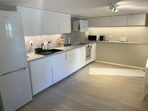 a kitchen with white cabinets and white appliances at One bedroom basement apartment in the city in Tromsø