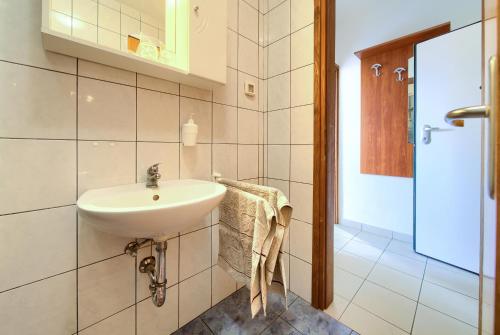 a white bathroom with a sink and a shower at Apartments Ada in Baška