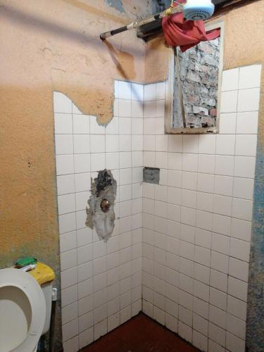 een badkamer met een toilet en een betegelde muur bij Casa familiar in Soacha