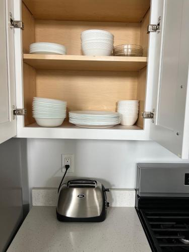 a tea kettle and plates in a kitchen cabinet at NEW 4-bed 4-bath Stylish House with Mountain View and 2 garages in Lehi