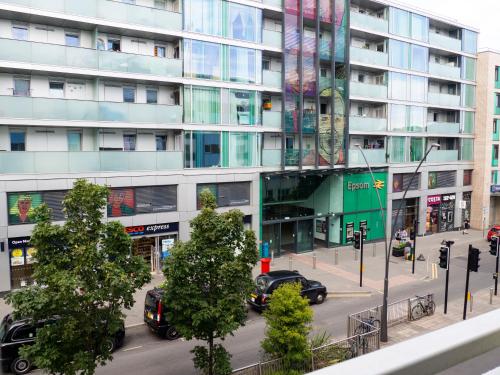 a city street with cars parked in front of a tall building at Stylish 2 bedroom apartment in the heart of Epsom town centre in Epsom