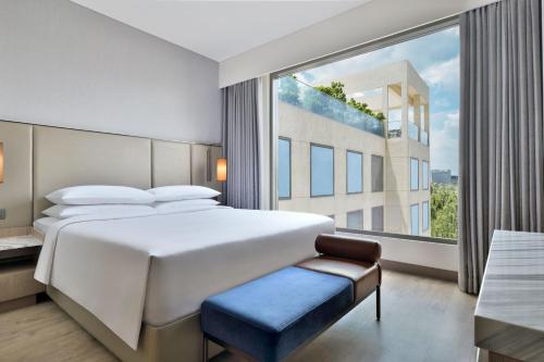 Marriott Executive Apartments Navi Mumbai في نافي مومباي: غرفة نوم بسرير كبير ونافذة كبيرة