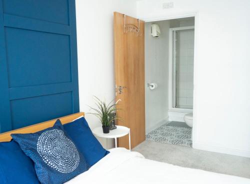 una camera da letto con una parete con accento blu e un letto con cuscini blu di Stylish 2 bedroom apartment in the heart of Epsom town centre a Epsom
