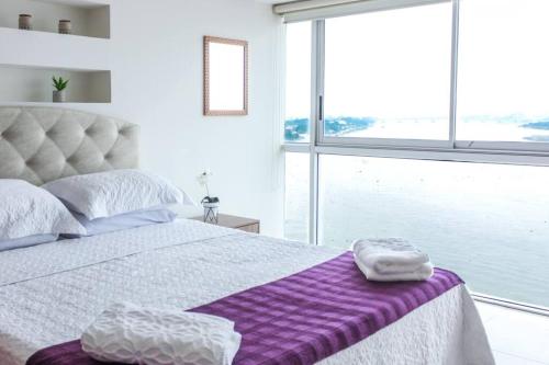 um quarto com uma cama com um cobertor roxo em Suite 806 extraordinaria vista al rio con piscina. em Guayaquil
