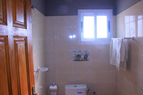 a bathroom with a toilet and a window at Le beau séjour - Maison meublée 3 pièces in Libreville