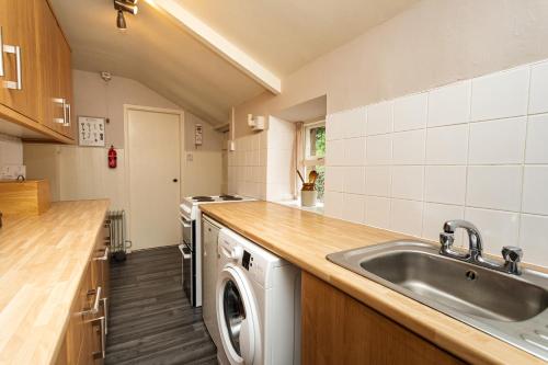 a kitchen with a sink and a washing machine at Bilton Farm Cottage No2 in Alnmouth