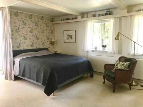 a bedroom with a bed and a chair and windows at Staevnegaarden in Flødstrup