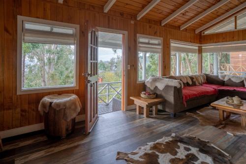 a living room with a couch and large windows at Cabaña puerto varas, a orillas del Lago LLanquihue in Puerto Varas