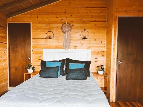 ein Schlafzimmer mit einem weißen Bett mit blauen Kissen in der Unterkunft Monte Santa Elena in Medellín