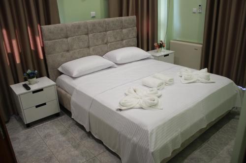 um quarto com uma cama branca com toalhas brancas em Hotel Mondo em Gjirokastër