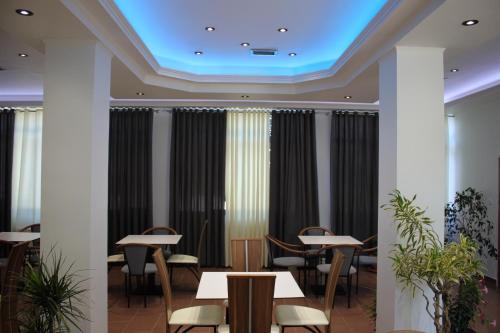a restaurant with tables and chairs and a blue ceiling at Hotel Mondo in Gjirokastër