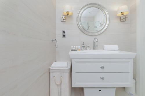 a white bathroom with a sink and a mirror at Seaside Sopot Apartment with Parking and Gym by Renters in Sopot