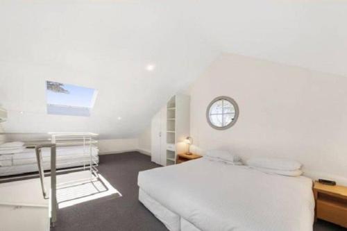 a white bedroom with a bed and a clock on the wall at Oceanic Apartment Sorrento in Sorrento