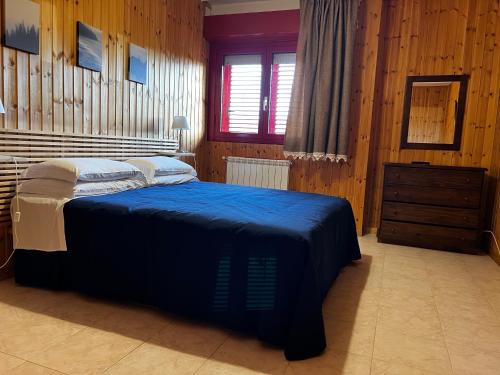 a bedroom with a blue bed and a wooden wall at Bed 100s in Livata