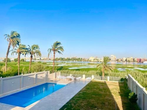 a house with a swimming pool and palm trees at Royal Nile Villas - Nile View Apartment 2 in Luxor