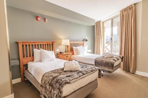 a hotel room with two beds and a window at Cascade in Whistler