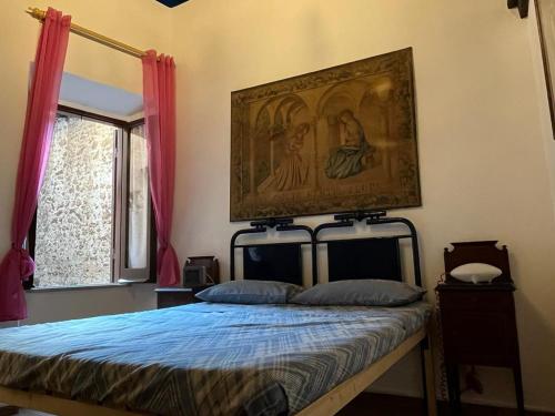 een slaapkamer met een bed met een schilderij aan de muur bij Antico Oratorio dei Razza in Sermoneta