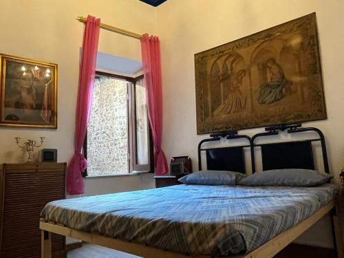 een slaapkamer met een bed met een schilderij aan de muur bij Antico Oratorio dei Razza in Sermoneta