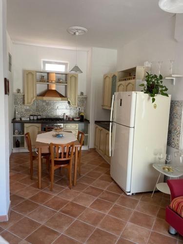 een keuken met een tafel en een witte koelkast bij Le Maioliche in Saponara Villafranca