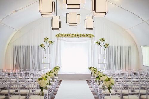 a wedding ceremony room with white chairs and a chandelier at Hilton Short Hills in Short Hills