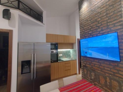une cuisine avec une grande télévision à écran plat sur un mur en briques dans l'établissement Balkanska Four Seasons Suites, à Belgrade
