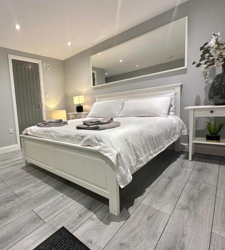 a bedroom with a large white bed with a large mirror at Modern Luxury Private Detached 1 Double Bedroom Studio Apartment - Super Fast Wifi in Luton
