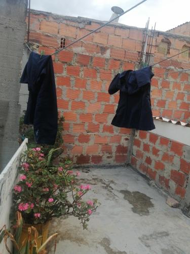 two black coats hanging on a brick wall at Casa familiar en Soacha in El Apogeo